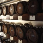 Wooden barrels stacked on shelves in a dimly lit cellar. Perfect for storing aging wine or balsamic vinegar.