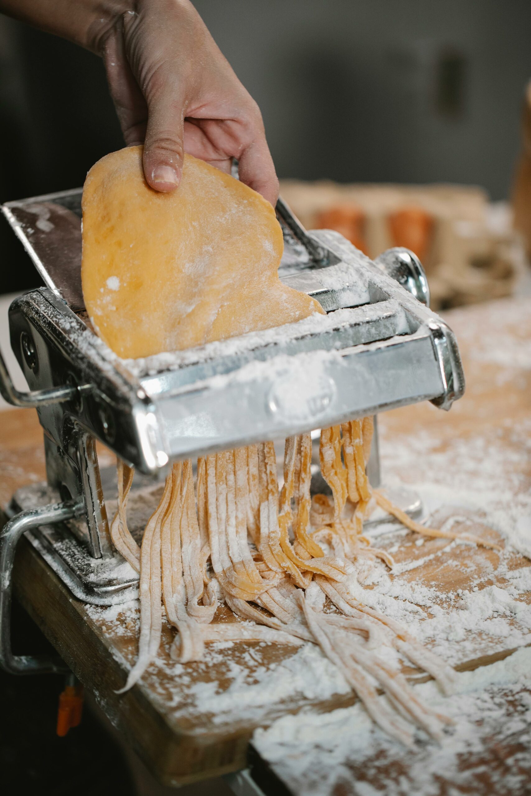 Handmaking fresh pasta with a pasta machine on a floured surface.